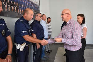 Komendant wręcza policjantowi Wydziału Ruchu Drogowego medal pamiątkowy.