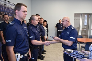 Komendant wręcza policjantowi medal pamiątkowy.